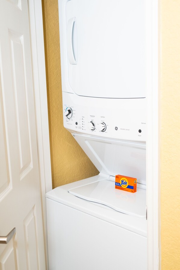 Une vue de face d’un lave-linge blanc, avec ses boutons de commande et une boîte de lessive Tide posée sur le dessus.