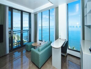 Une chambre d’hôtel moderne dotée d’un grand balcon, d’un canapé, d’une petite table et offrant une vue sur la mer.