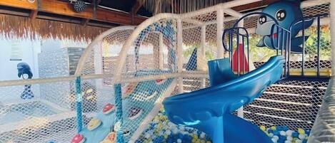 Zona de juegos infantiles con piscina de pelotas y tobogán.