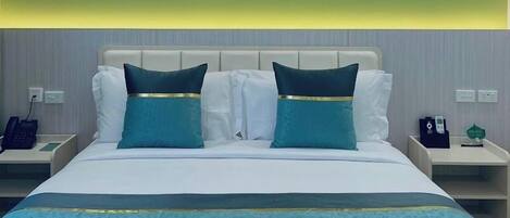 A hotel room with a large bed, two nightstands, a painting above the bed, and a green wall.