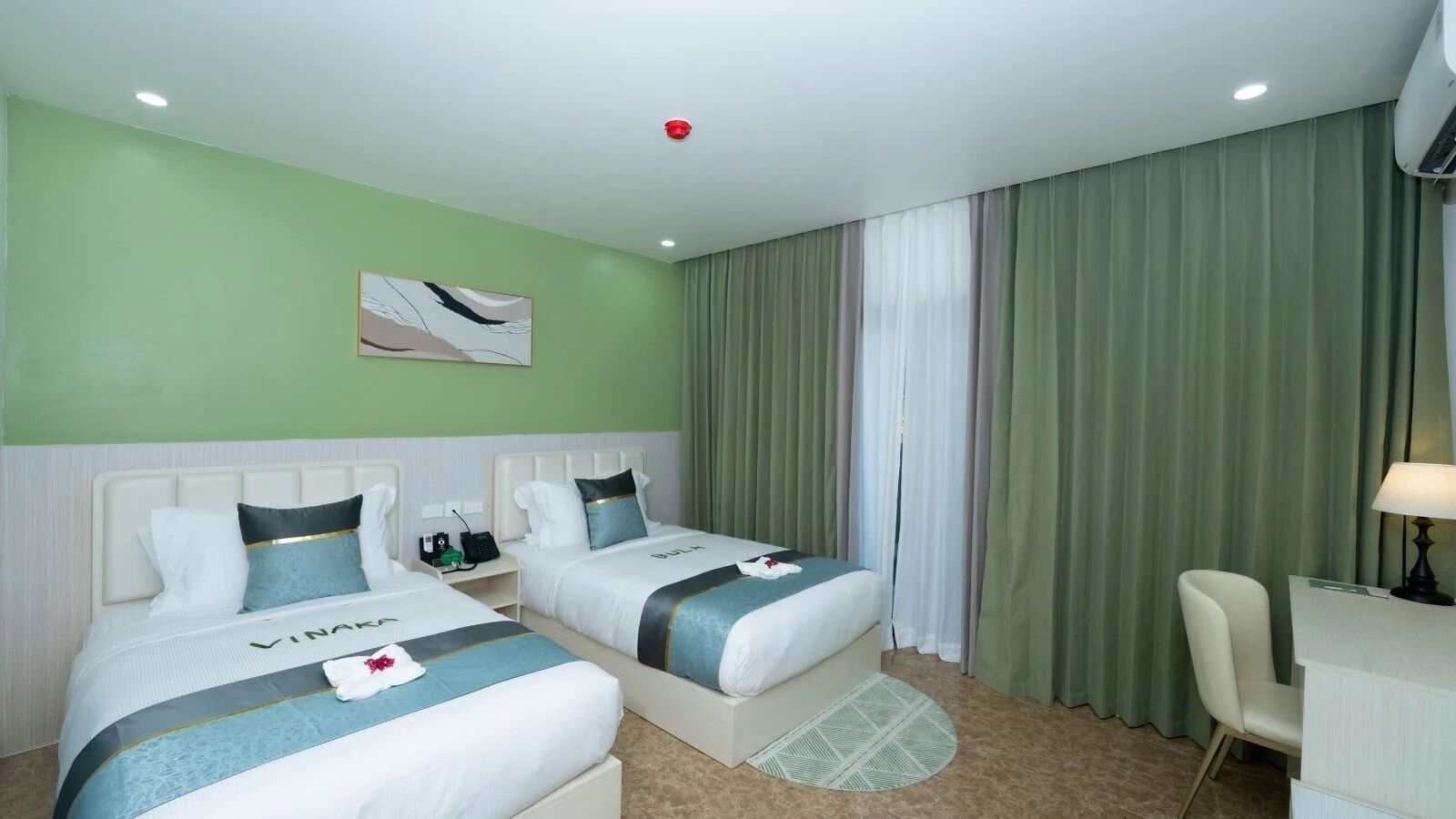 Una camera d'albergo con due letti, una scrivania e una sedia.