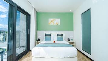A modern bedroom with a large bed, green walls, and a view through a sliding glass door.