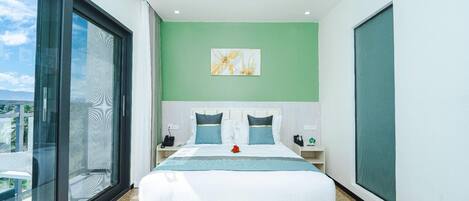 A modern bedroom with a large bed, green walls, and a view through a sliding glass door.