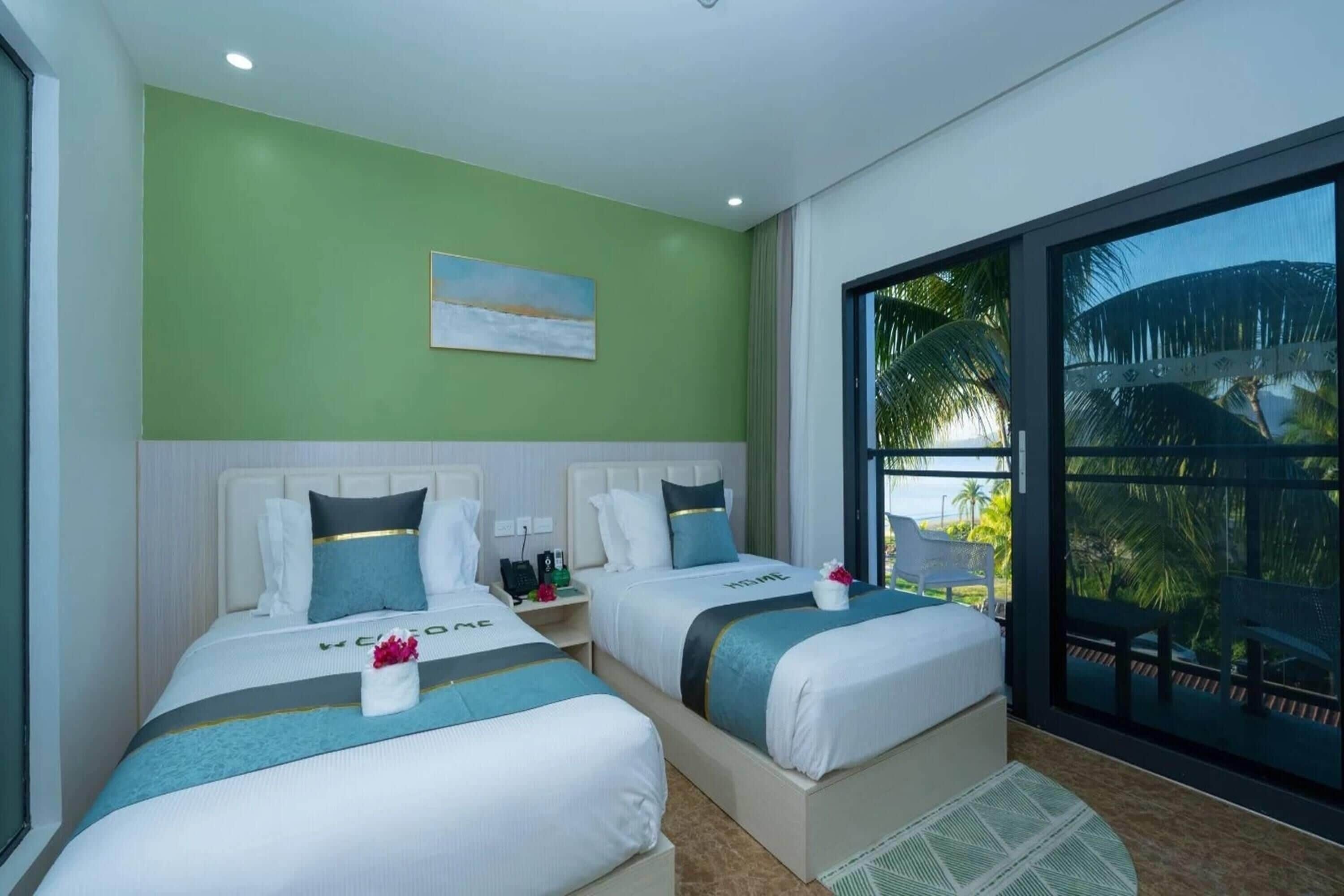 A hotel room with two beds, a large window with a view of palm trees, and a painting on the wall.