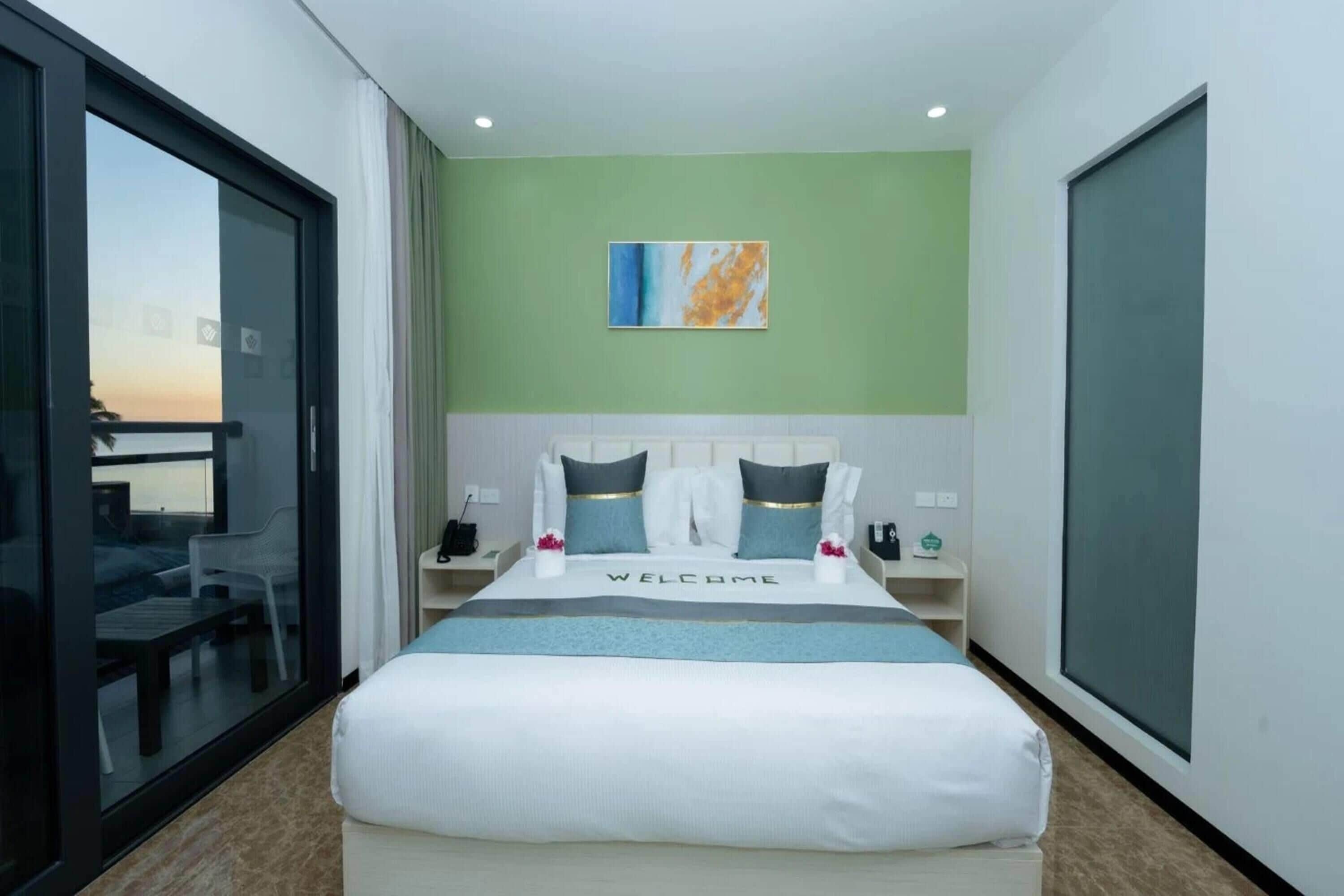 Una habitación de hotel con cama, mesita de noche, ventana y vista al exterior.