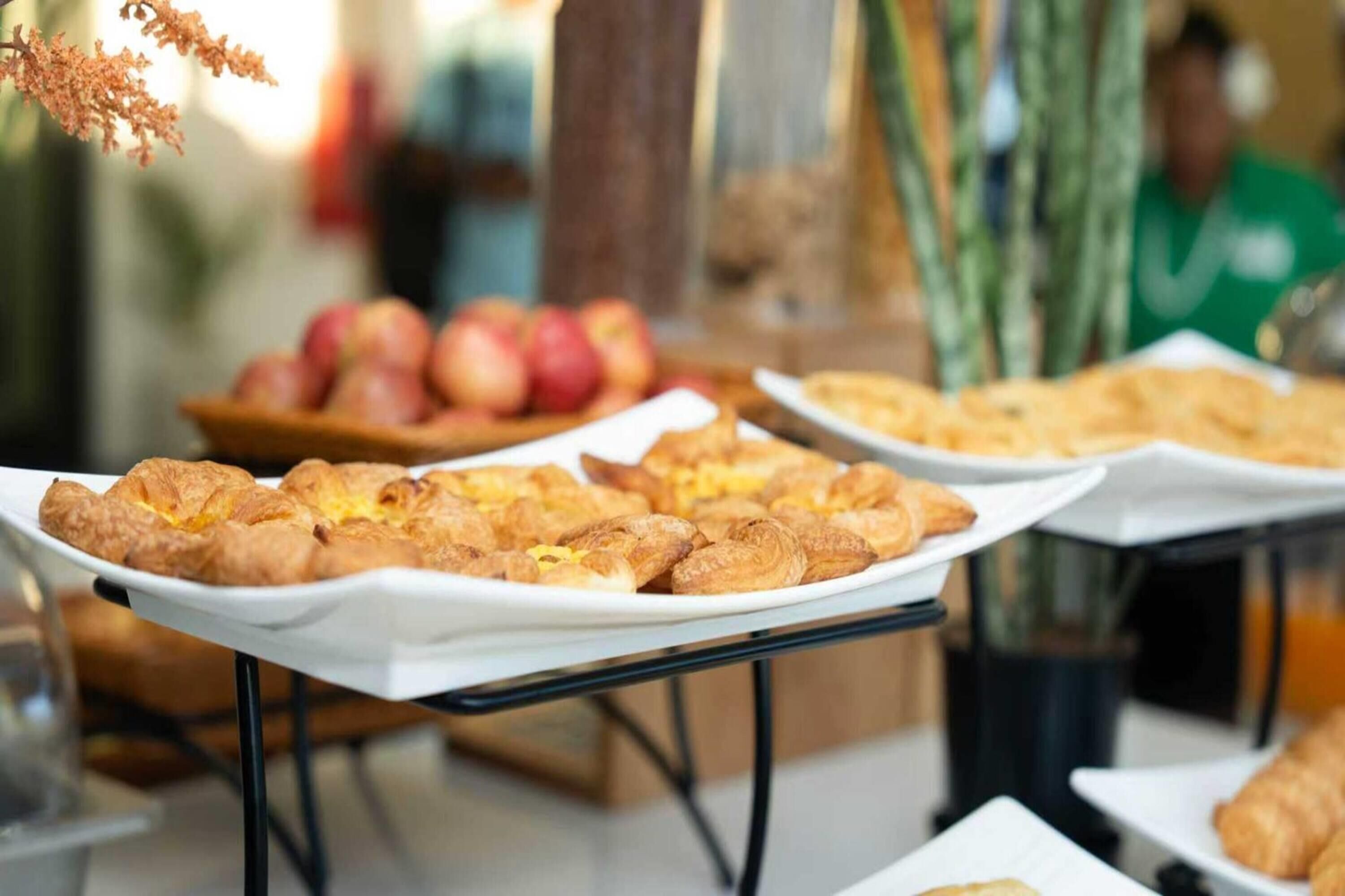 A buffet table with pastries and a bowl of apples.