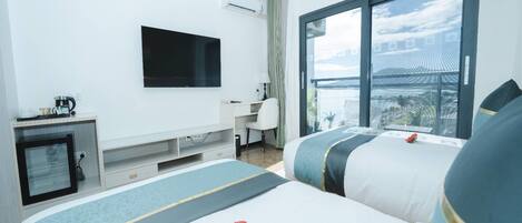 A hotel room with two beds, a desk, a TV, and a large window with a view.