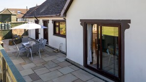 A patio with a table and chairs, a covered area, and a view of the interior through a glass door.