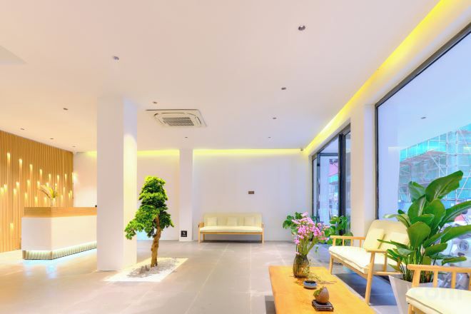 A modern interior with a reception desk, seating area, and large windows.