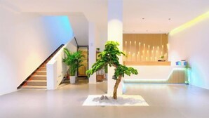 Ein modernes Interieur mit einer Treppe, einem Empfangstresen und einem Blumentopf.