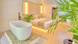 Ein modernes Schlafzimmer mit einer großen Badewanne, einem Bett mit Kopfteil und einer Topfpflanze.