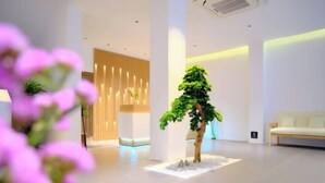 Eine moderne Lobby mit einer Rezeption, einer Sitzecke und einem dekorativen Baum.