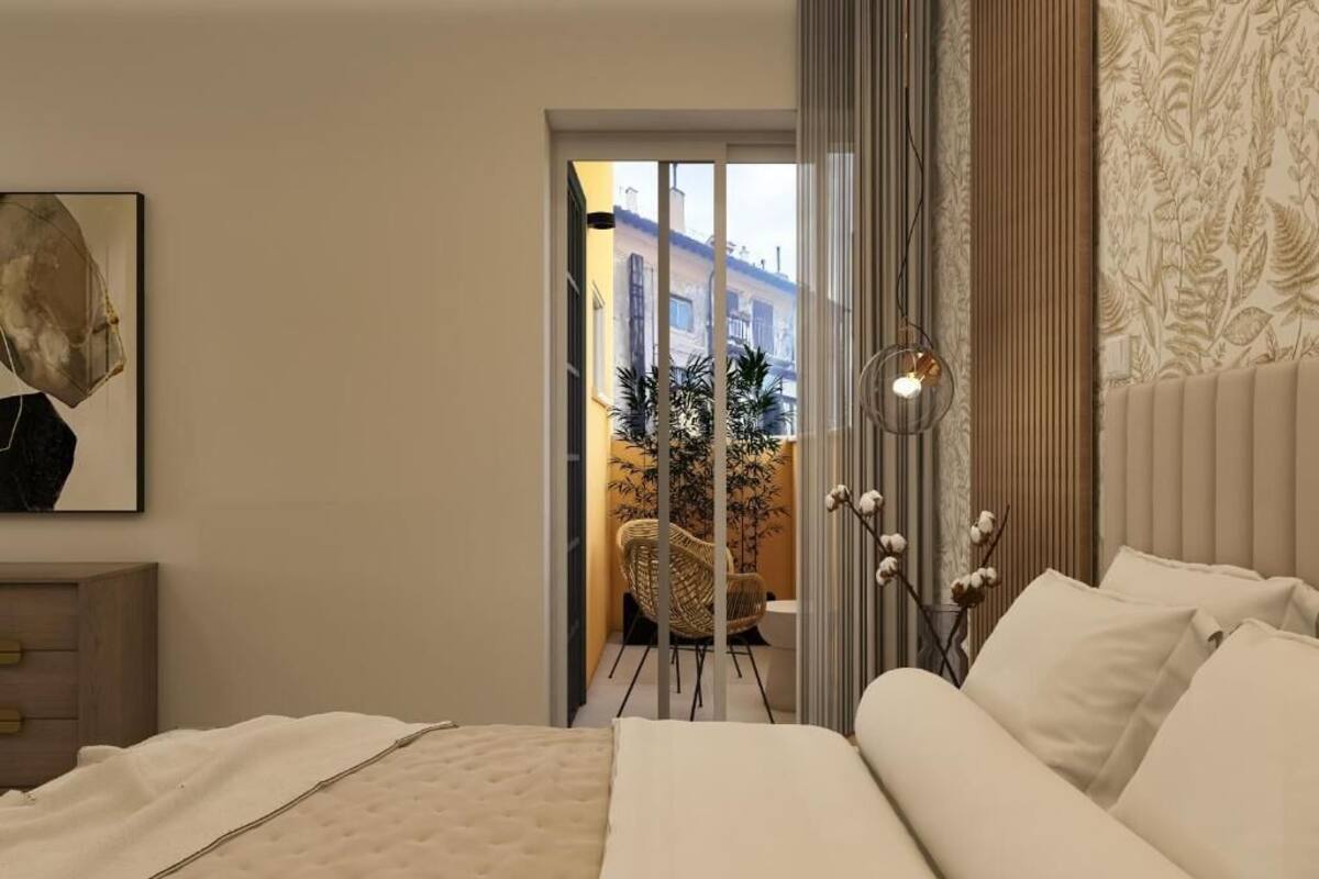 A bedroom with a bed, a nightstand, a chair, and a view of the outside.