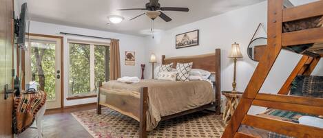Um quarto com cama, ventilador de teto, janela e porta.