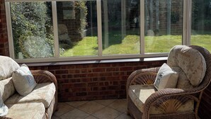 Un invernadero con muebles de mimbre y vistas a un jardín.