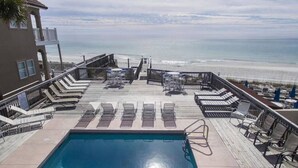Ein Poolbereich mit Liegestühlen und Blick aufs Meer.