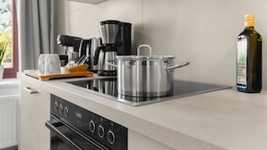 A modern kitchen with a built-in stove, a coffee maker, and a bottle of olive oil on the counter. - ElbDreams Cozy Design Apartment (Dresden)