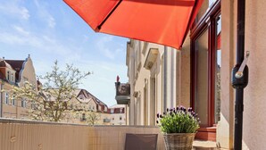 A balcony with a red umbrella, a wicker basket with flowers, and a table with chairs. - ElbDreams Cozy Design Apartment (Dresden)