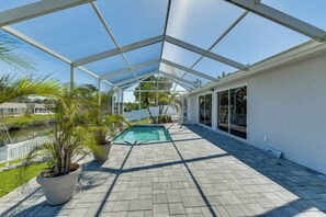 A covered outdoor area with a pool, potted plants, and a view of the surrounding landscape.