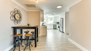 Una cucina moderna con un'isola centrale, sgabelli da bar e un orologio decorativo al muro.