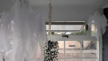A room with a large window, a hanging macrame piece, and a plant.