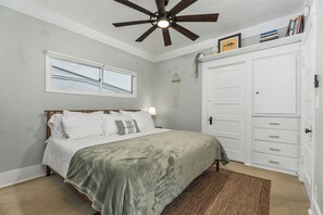 A bedroom with a bed, a ceiling fan, a window, a wardrobe, and a bedside lamp. - CozyVibeStay . King Bed. Parking. Walk to Beach (Long Beach)