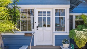 A house with a white front door, multiple windows, and a blue exterior. - CozyVibeStay . King Bed. Parking. Walk to Beach (Long Beach)