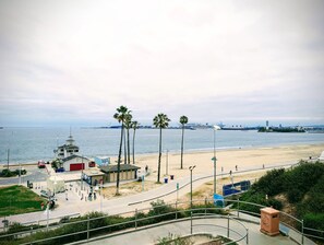 A coastal view with a beach, palm trees, and a lighthouse.