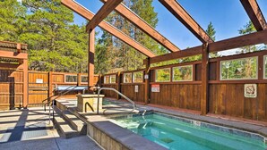 Un'area piscina in legno con una scala e gradini in metallo che conducono in acqua.