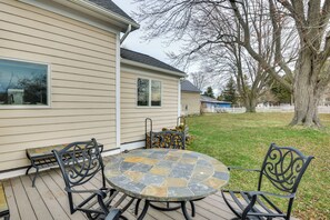 Une terrasse avec une table ronde et des chaises, un banc et un petit objet décoratif sur la plateforme.