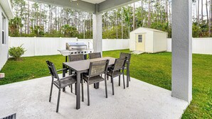An outdoor patio with a grill, dining table, and chairs. - 7 Mi to Flagler Beach: Breezy Stay w/ Pool Access! (Palm Coast)