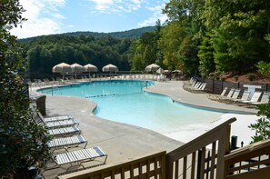 A swimming pool with lounge chairs and umbrellas, surrounded by trees and hills. - Lake & Golf Course Views: Big Canoe Home w/ Deck! (Jasper)
