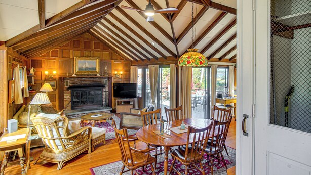 A cozy living room with a fireplace, wooden furniture, and a dining area. - Steps to Beach: Timeless Home w/ Cotuit Bay View! (Cotuit)