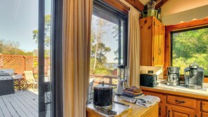 A kitchen with a large window, wooden cabinets, and a countertop with kitchen appliances. - Steps to Beach: Timeless Home w/ Cotuit Bay View! (Cotuit)