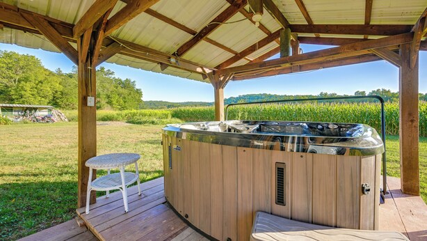 Eine Holzterrasse mit einem Whirlpool, einem kleinen Tisch und einer Bank.