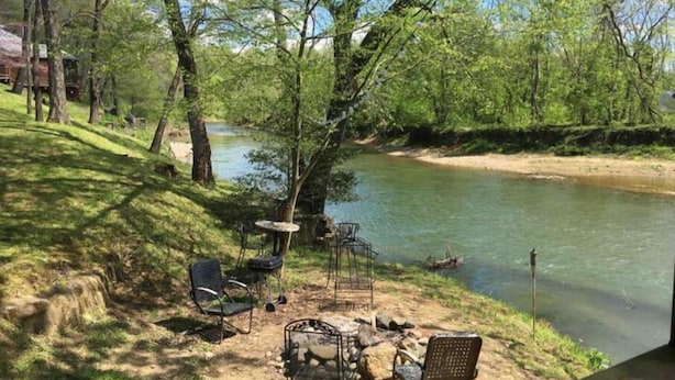 A riverside campsite with a table and chairs, a grill, and a small table. - Pop's Place on the Rapidan River. (Rochelle)