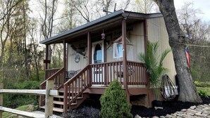 A cabin with a wooden deck, a small porch, and a stone pathway leading to the entrance. - Pop's Place on the Rapidan River. (Rochelle)