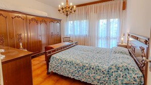 Een slaapkamer met een groot bed, een houten garderobe en een kroonluchter.
