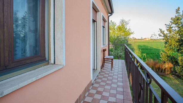 Een balkon met uitzicht op een groen veld en bomen.