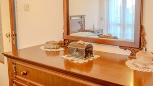Een houten dressoir met een spiegel, twee decoratieve dozen en een kantplooi.
