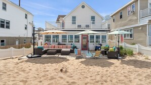A beachfront property with a covered patio, outdoor seating, and a pool.