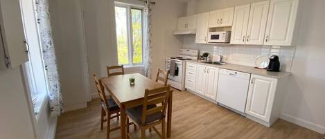 Kitchen area with dining table for four, microwave, coffee maker, and dishwasher.