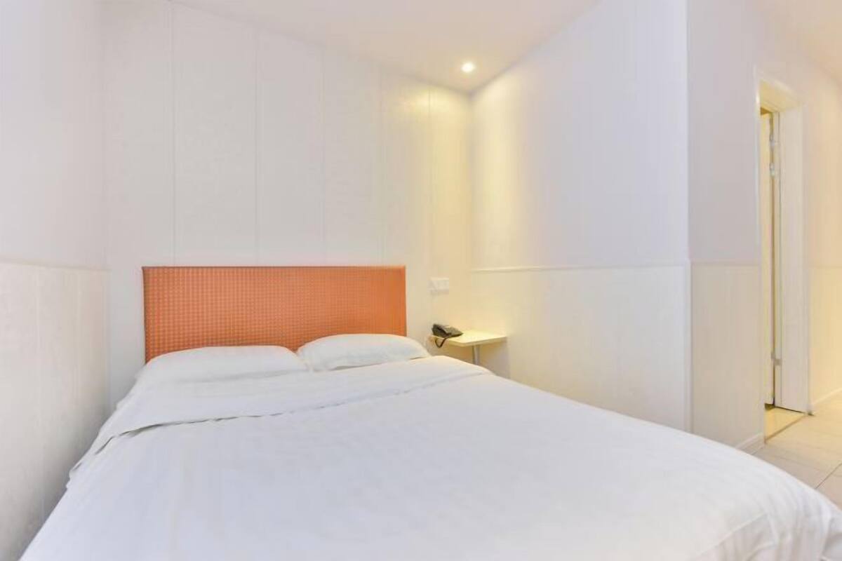 A hotel room with a bed, a nightstand, and a door.