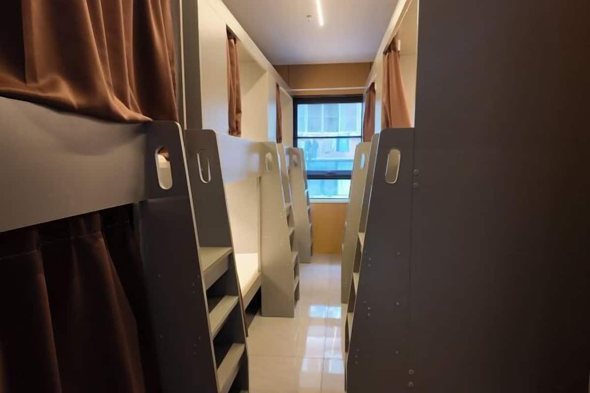 A narrow corridor with bunk beds and a window at the end.