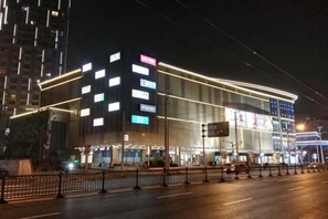 A modern building with multiple floors, large windows, and illuminated signage. - Xiangru Chain Hotel (Shanghai Caogen (Shanghai)