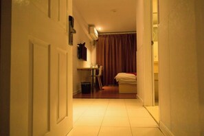 A narrow hallway leading to a room with a bed, a small table, and a chair. - Xiangru Chain Hotel (Shanghai Caogen (Shanghai)