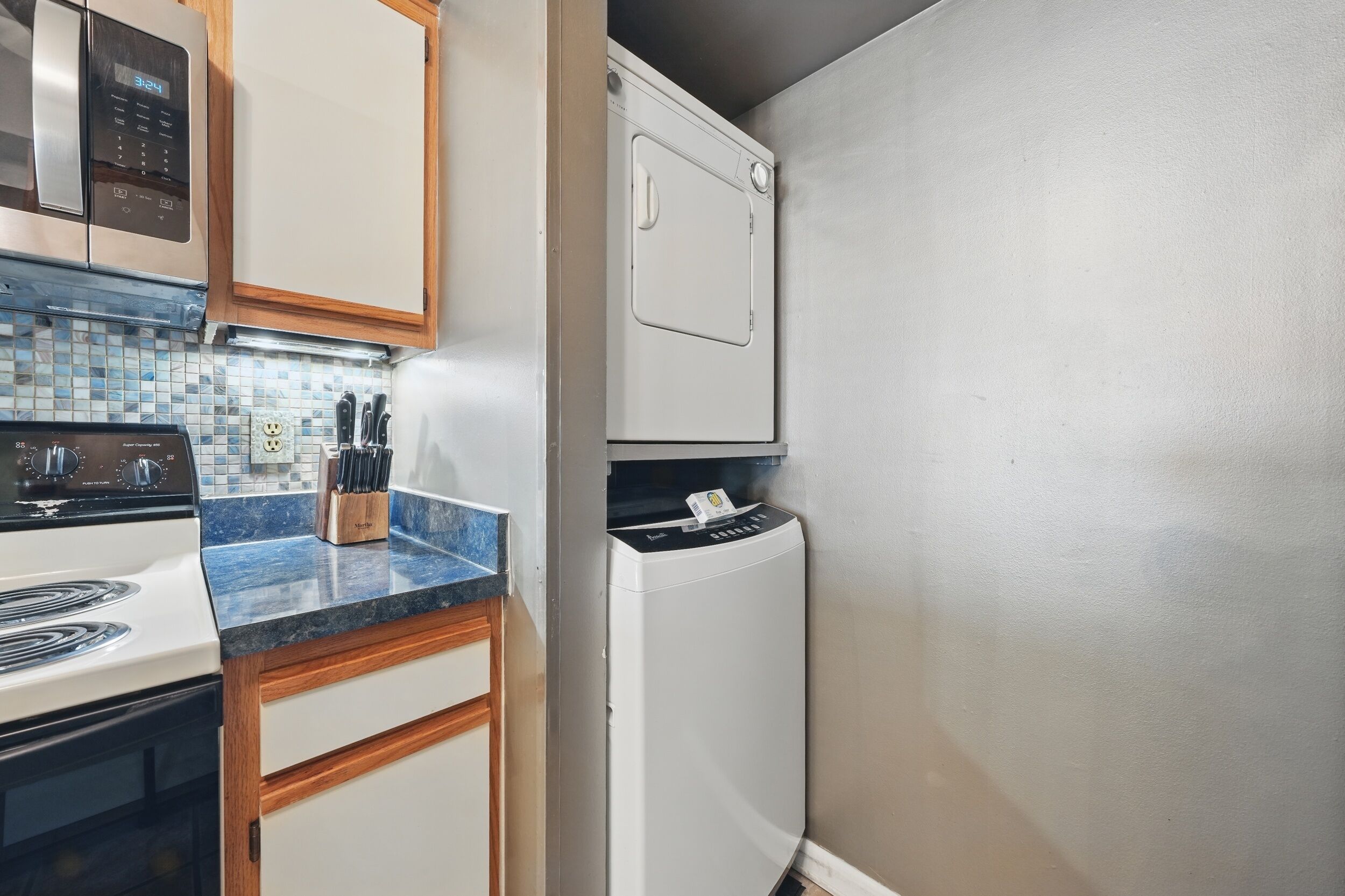 A compact kitchen with a white stove, a microwave, and a built-in dishwasher.