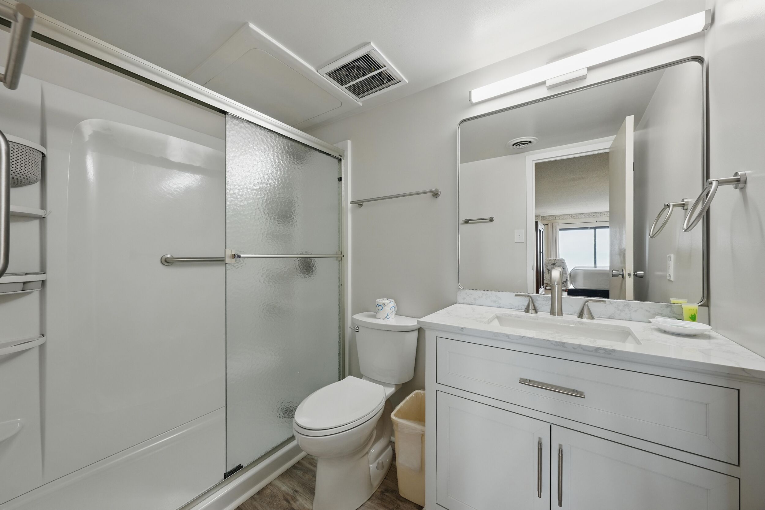 A modern bathroom with a glass shower enclosure, a toilet, and a vanity with a mirror.
