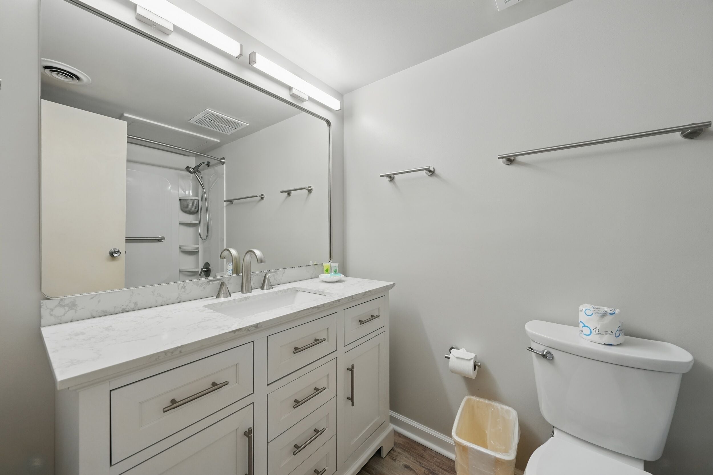 Un bagno moderno con lavandino, specchio e water bianchi.