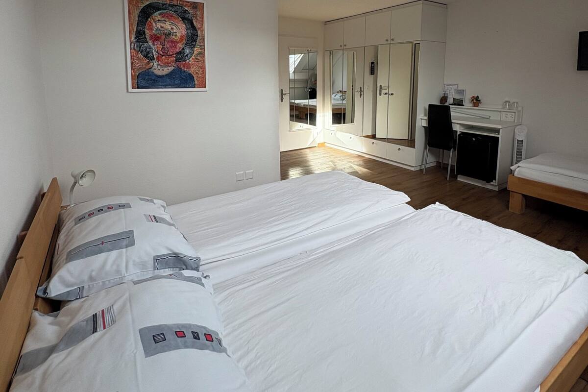 Une chambre d’hôtel avec deux lits, un bureau et une armoire.
